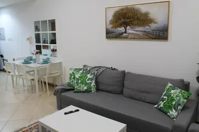a living room with a gray couch and a table at Bright and beautiful one bedroom apartment close to metro and beach in Dubai