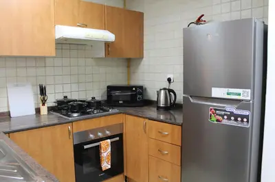 a kitchen with a stainless steel refrigerator and wooden cabinets at Bright and beautiful one bedroom apartment close to metro and beach in Dubai