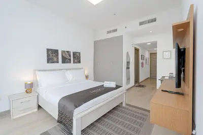 a bedroom with a bed and a flat screen tv at Escape24 Cozy Studio with City View in JVC in Dubai