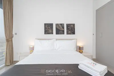 a bedroom with a large white bed with three pictures on the wall at Escape24 Cozy Studio with City View in JVC in Dubai