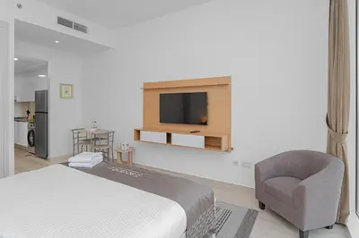 a bedroom with a bed and a chair and a television at Escape24 Cozy Studio with City View in JVC in Dubai