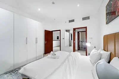 a white bedroom with a white bed and a chair at FIRST CLASS 2BR Elite Urban Retreat in Dubai
