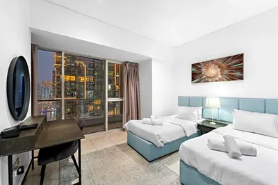 a hotel room with two beds and a desk and a window at FIRST CLASS 2BR Elite Urban Retreat in Dubai