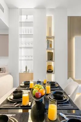 a table with a bowl of fruit and glasses of orange juice at FIRST CLASS 3BR Trendy Urban Hideaway in Dubai