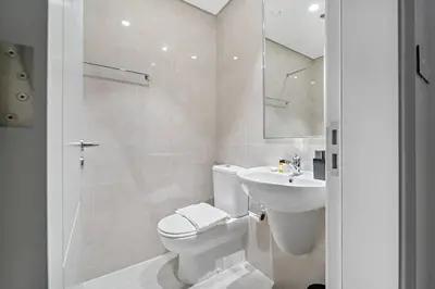 a white bathroom with a toilet and a sink at FIRST CLASS 3BR Trendy Urban Hideaway in Dubai