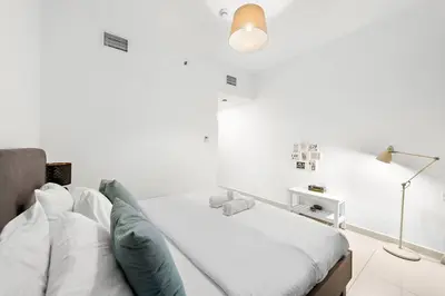 a white bedroom with a bed and a lamp at Luxury 2BR with Stunning Dubai Marina Views Near JBR Beach in Dubai