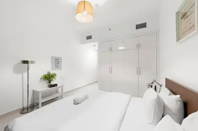 a white bedroom with a bed and a shower at Luxury 2BR with Stunning Dubai Marina Views Near JBR Beach in Dubai