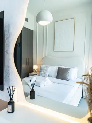 a bedroom with a white bed and a mirror at Burj Khalifa Bliss I 4 bedroom Apartments I Burj Khalifa & Fountain Views I Free Gym, Pool, Parking, Wi-Fi and PS5 I by Skyline Serenity in Dubai