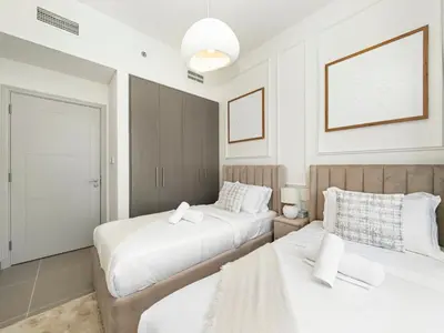two beds in a room with white walls at Burj Khalifa Bliss I 4 bedroom Apartments I Burj Khalifa & Fountain Views I Free Gym, Pool, Parking, Wi-Fi and PS5 I by Skyline Serenity in Dubai