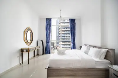 a bedroom with a bed and a mirror and a chair at Elegant Escapes - Homely 1B in Dunya Tower in Dubai