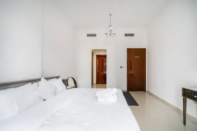 a white bedroom with a large bed with white sheets at Elegant Escapes - Homely 1B in Dunya Tower in Dubai