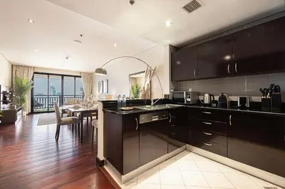 a kitchen with black cabinets and a dining room at Beachfront Residences with Full Sea and Burj AlArab Views in Luxury Resort in Dubai