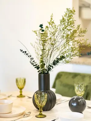 a table with a black vase with flowers in it at Stunning Two Bedroom Apartment with Private Balcony & Burj Khalifa by Luxury Space in Dubai