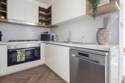 a white kitchen with a sink and a dishwasher at Frank Porter - Downtown Views II Tower 1 in Dubai