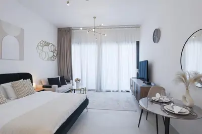 a white bedroom with a large bed and a table at Elegant Studio in Binghatti Canal in Dubai