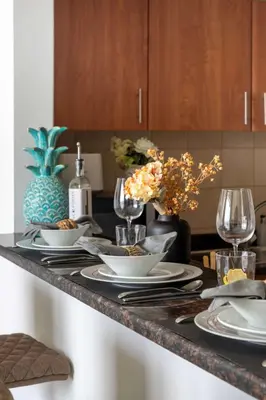 a kitchen counter with a table with plates and wine glasses at Frank Porter - Golf Tower 3 in Dubai