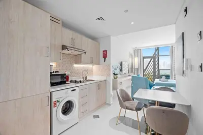 a kitchen with a washing machine and a table and chairs at Goldbest - Seven Palm 4ppl in Dubai