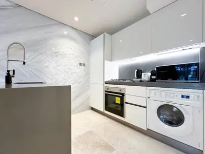 a white kitchen with a washer and dryer at Trophy - Elevated Living in Luxurious Business Bay Loft in Dubai