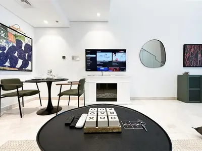 a living room with a table and a tv at Trophy - Elevated Living in Luxurious Business Bay Loft in Dubai
