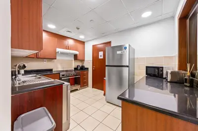 a large kitchen with a stainless steel refrigerator at Prime Spacious 5 Plus 1 BR Apt On JBR Beach near Metro ,Walk to The Mall, Dining & Entertainment - By Sunkissed Holiday Homes in Dubai