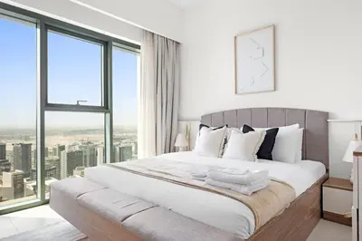a white bedroom with a large bed with windows at Silkhaus High Floor Luxury 1 BDR with Stunning View in Dubai
