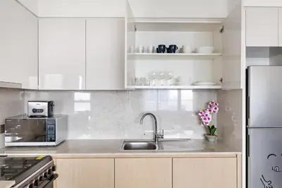 a white kitchen with a sink and a microwave at Silkhaus High Floor Luxury 1 BDR with Stunning View in Dubai