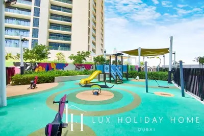 a playground in front of a building with a sign that reads us holiday home at LUX The Aykon Suite in Dubai