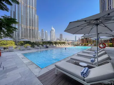 a swimming pool with lounge chairs and an umbrella at Dream Inn - Address Dubai Opera Residences in Dubai