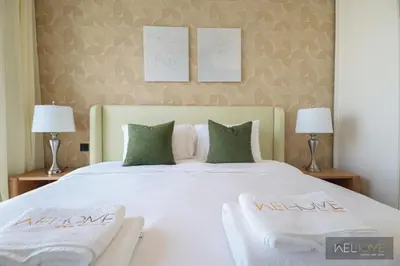 a bedroom with a large white bed with two chairs at WelHome - Fancy 1BR Apt at Dubai Hills near Dubai Hills Mall in Dubai