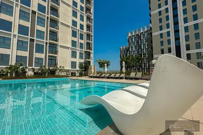 a swimming pool with a white chair next to some buildings at WelHome - Fancy 1BR Apt at Dubai Hills near Dubai Hills Mall in Dubai