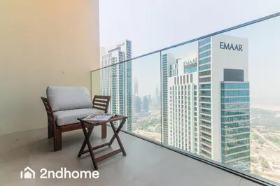 a chair on a balcony with a view of the city at 2ndHome - Downtown Views 1 in Dubai