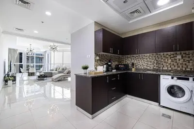 a kitchen with a washing machine and a living room at Luxury 1-BR with Lake View in Business Bay in Dubai