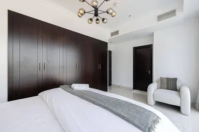 a bedroom with a large white bed and a chair at Luxury 1-BR with Lake View in Business Bay in Dubai