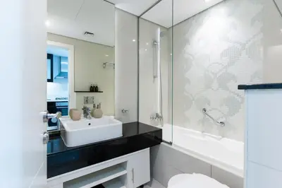 a white bathroom with a sink and a mirror at Canal View l Hotel Studio l Great Amenities in Dubai