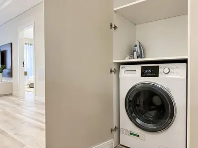 a washer and dryer in a white laundry room at Elegantly Renovated 1BR Apartment at 5 Star Resort in Dubai
