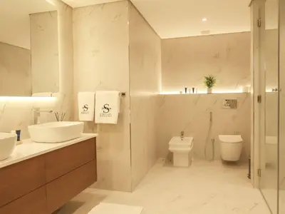 a white bathroom with a sink and a toilet at Stunning Renovated 1BR Apartment at 5 Star Resort in Dubai