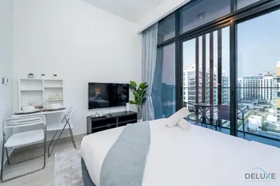a bedroom with a bed and a desk and a large window at Inviting Studio Apartment at Azizi Riviera 36 in Al Merkadh by Deluxe Holiday Homes in Dubai