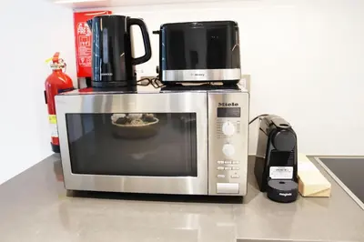 a microwave with a coffee maker on top of it at Stellar Dreams 1BR - District 1 in Dubai