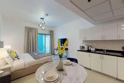 a kitchen and a living room with a table at Comfy Studio Apartment in DIFC in Dubai