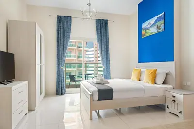 a bedroom with a bed and a blue wall at New Studio in Sport City - Pool, Gym, Parking in Dubai