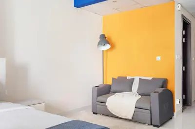 a bedroom with a chair and a yellow wall at New Studio in Sport City - Pool, Gym, Parking in Dubai