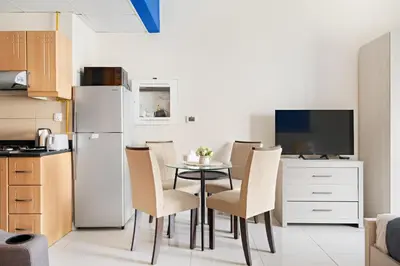 a kitchen with a table and chairs and a refrigerator at New Studio in Sport City - Pool, Gym, Parking in Dubai