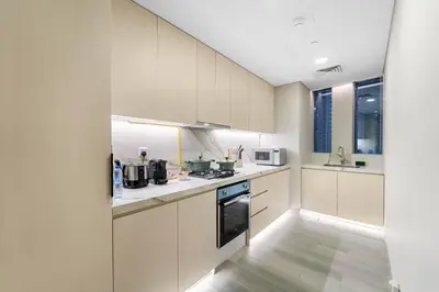 a kitchen with white cabinets and a stove top oven at Marina-View 1BR Escape Walk to Dining & Landmarks in Dubai