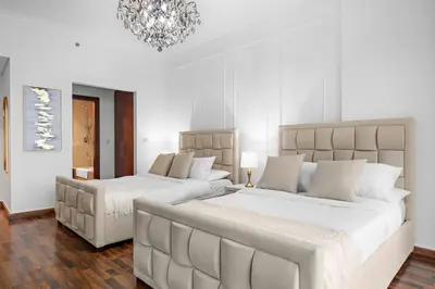 a white bedroom with two beds and a chandelier at Luxury 4BR Flat, Downtown Dubai, Pool, Gym, PS5, Sleeps 11 Guests in Dubai