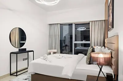 a white bedroom with a bed and a mirror at FIRST CLASS 1BR Luxury Living in DIFC in Dubai