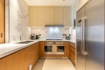a kitchen with wooden cabinets and a stainless steel refrigerator at Deluxe 3BR Home in Address Opera with Full Burj View in Dubai