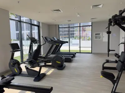 a gym with several treadmills and elliptical machines at Azizi Riviera 46 - Cosy Studio in Dubai