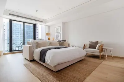 a white bedroom with a large bed and a chair at Frank Porter - Goldcrest Views 2 in Dubai