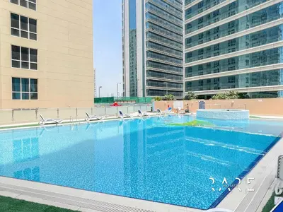 a large swimming pool in front of two tall buildings at Rare Holiday Homes - The Crescent Tower - IMPZ - Dubai Production City - R705 in Dubai