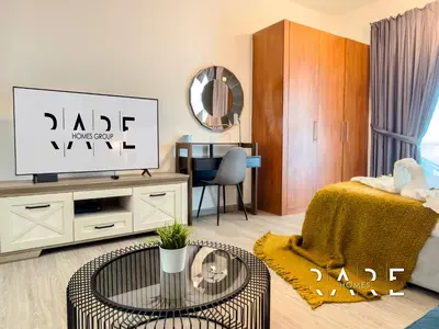 a living room with a tv and a table at Rare Holiday Homes - The Crescent Tower - IMPZ - Dubai Production City - R705 in Dubai